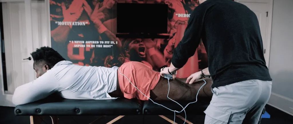 Grady Jarrett lying prone on treatment table receiving Volta X neuromuscular stimulation on his leg
